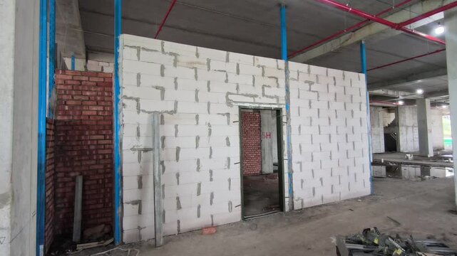Autoclaved aerated concrete AAC block wall installation on a construction site. Features metal stiffeners and lintels for structural efficiency. Modern masonry techniques speed up building progress.