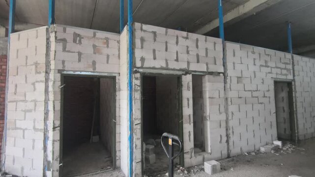 Autoclaved aerated concrete AAC block wall installation on a construction site. Features metal stiffeners and lintels for structural efficiency. Modern masonry techniques speed up building progress.