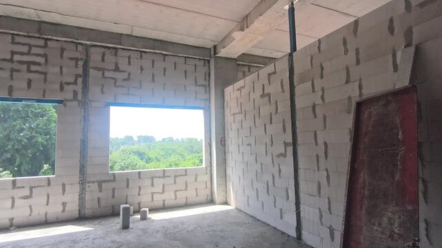 Autoclaved aerated concrete AAC block wall installation on a construction site. Features metal stiffeners and lintels for structural efficiency. Modern masonry techniques speed up building progress.