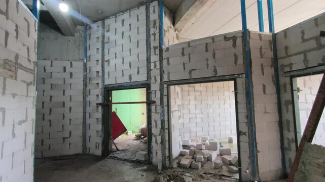 Autoclaved aerated concrete AAC block wall installation on a construction site. Features metal stiffeners and lintels for structural efficiency. Modern masonry techniques speed up building progress.