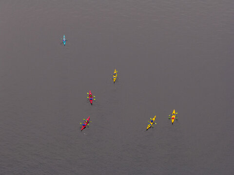 Aerial view of colorful kayaks paddling on the calm dark water in Valldal, More og Romsdal, Norway.