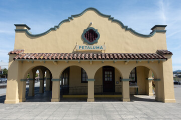 Obraz premium Historic Petaluma train station featuring Mission Revival architecture, arched colonnades, clay tile roofing, and the Petaluma name on the facade in Petaluma, California.