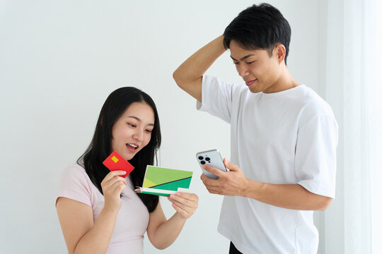 Young Japanese Couple Holding Bankbook and Credit Card at Home