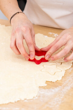 Baker work. Pastry culinary. Female chef hand cut star from rolled dough sheet on flour kitchen table with traditional cookies tool.