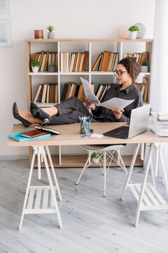 Manager lifestyle. Office atmosphere. Creative business woman analyzing document using notebook laptop at desk at professional workplace.