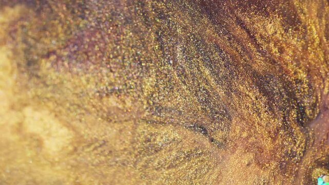 Bright ink spill. Vibrant fluid. Defocused yellow orange color paint glitter texture sparkling crystal spreading on abstract bokeh light background.