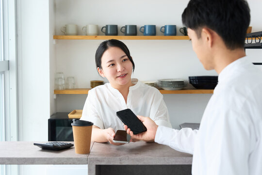 Young Japanese Woman Making Cashless Payment with Smartphone at Cafe Counter