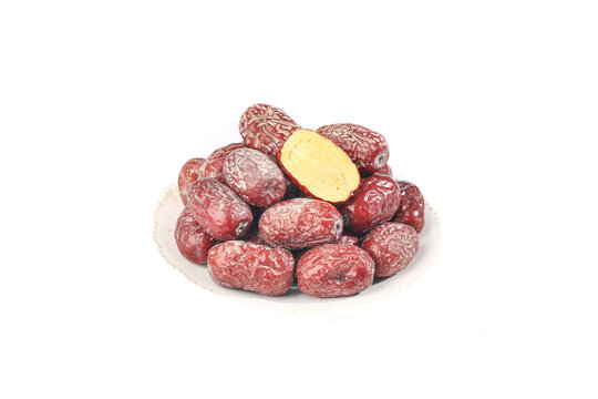 Dried Red Jujube Dates from Ruoqiang Xinjiang China on White Plate with Cut Open Fruit Showing Interior