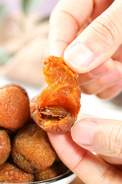 Hand Holding Dried Apricot Fruit Snack from Xinjiang China Showing Orange Flesh and Natural Pit Inside