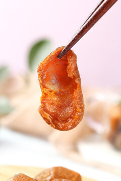 Dried Apricot Snack from Xinjiang China Held with Tweezers Close-up