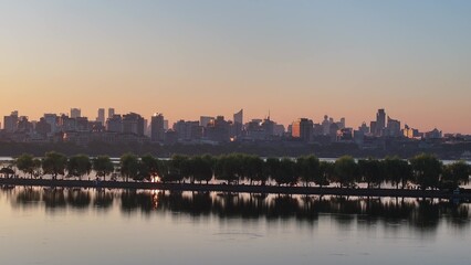 Fototapeta premium City skyline at dusk reflecting on calm water surface
