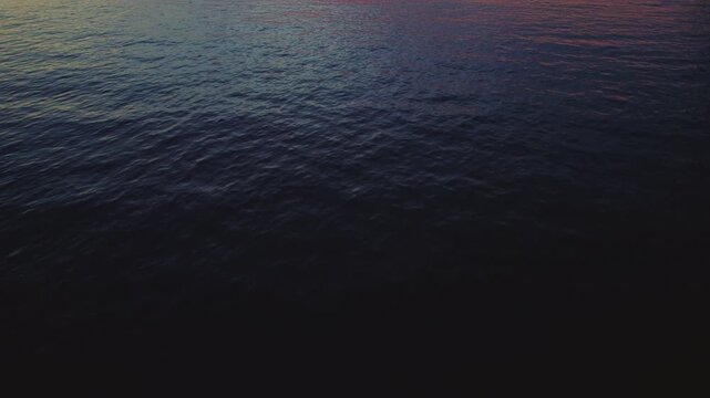 Sunset light reflecting on dark calm Ionian Sea waters on a tranquil evening in Greece