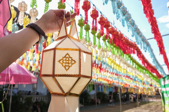 Woman's hand showing a traditional paper lantern during Yi peng (or Yee peng) festival in Wat Phra That Hariphunchai, Lamphun province, Thailand.