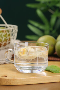 Luo Han Guo Monk Fruit Herbal Tea in Glass Mug Studio Shot with Tropical Plants Background