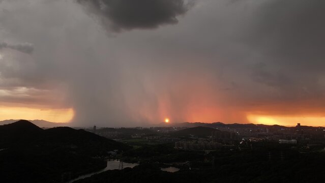 Heavy rain storm over city at sunset with dramatic dark clouds