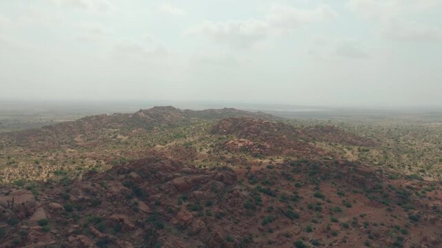 Rocky hills rise from a semi arid plain in the Thar Desert of Sindh, filmed by drone.