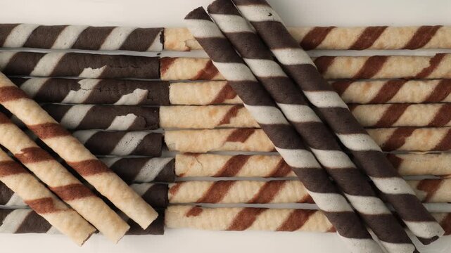 Dolly shot of striped chocolate rolled wafer sticks isolated on white background