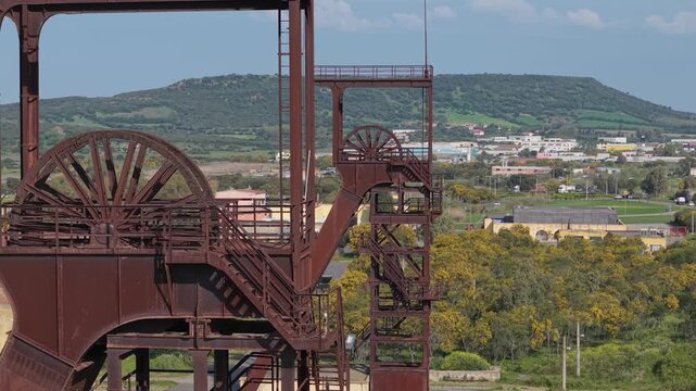 Historic Winding Tower, Used To Hoist Miners And Coal At Serbariu Coal Mine (Grande Miniera di Serbariu) In Carbonia, Sardinia, Italy. - aerial closeup shot