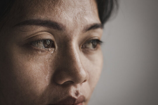 A sad woman crying in emotional distress, reflecting family problems, abuse, trauma, depression, fear, human trafficking, and the need for safety, care, and support.
