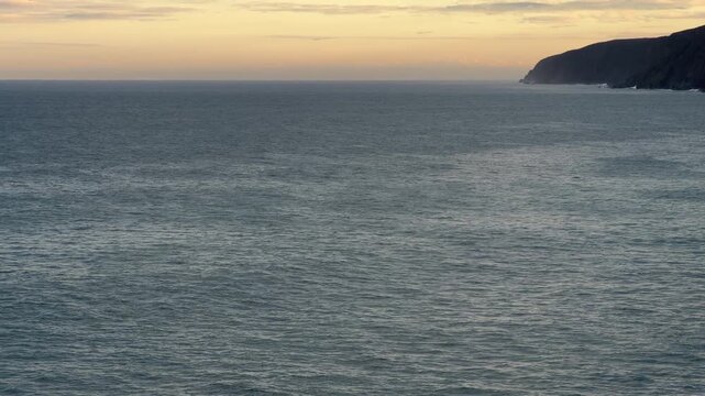 Calm ocean water texture with horizon and cliffs as a background in 60FPS 4K video footage