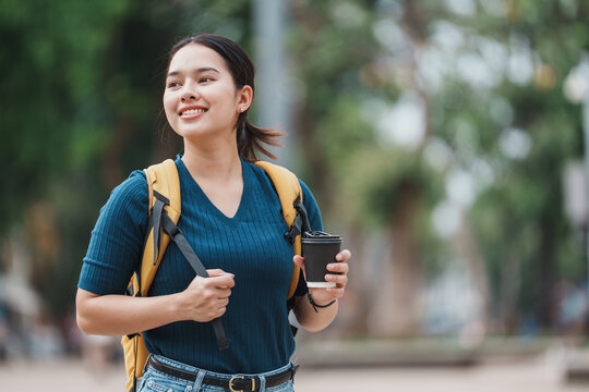 Student walking on campus holding coffee cup smiling