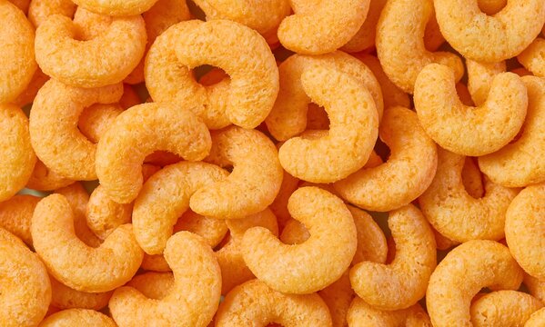  a dense pile of golden-orange curved corn flips filling the entire frame