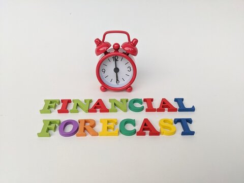 Red alarm clock above colorful letters spelling financial forecast, symbolizing timing and planning in economic analysis. Business concept background.