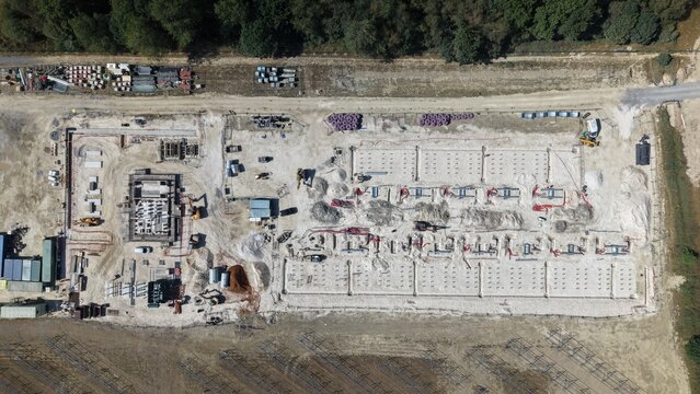 Aerial view of Common Park Solar Farm under construction showing foundation work, trenches, and construction equipment on a cleared site in Sheffield, England, United Kingdom.