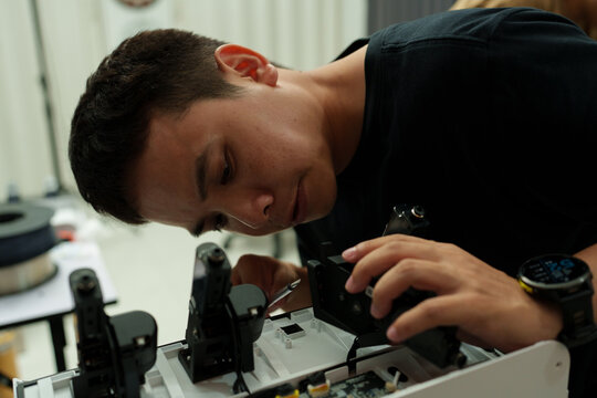The focus is on the hands of a technician setting up a 3D printer to print a clear white plastic model, using cutting-edge technology and concentrating on specific points within the laboratory.