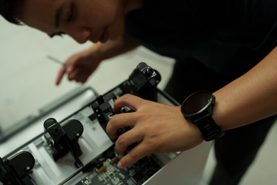 The focus is on the hands of a technician setting up a 3D printer to print a clear white plastic model, using cutting-edge technology and concentrating on specific points within the laboratory.