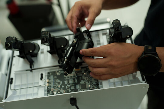The focus is on the hands of a technician setting up a 3D printer to print a clear white plastic model, using cutting-edge technology and concentrating on specific points within the laboratory.