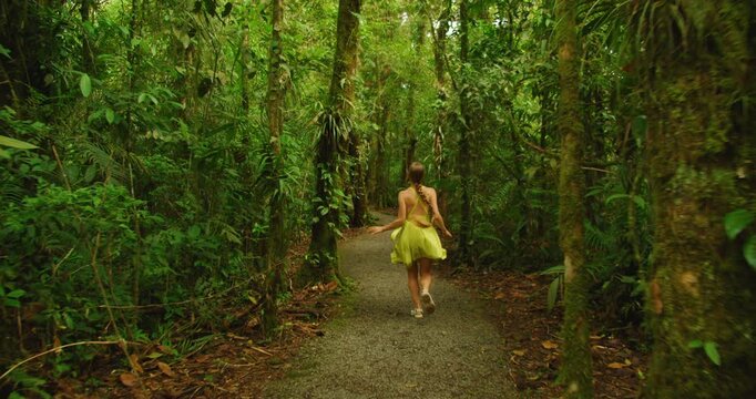 Woman running along small path in lush dense tropical cloud forest reserve in Costa Rica