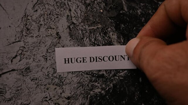 Huge Discount Promotion Card Placed by Hand on Rough Stone Texture Background