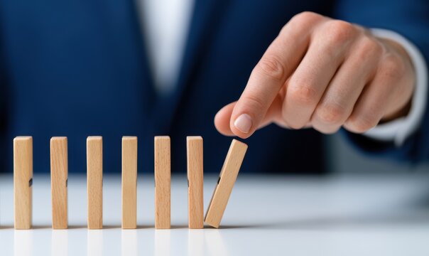 Business executive carefully positioning barriers among dominos to avoid a chain reaction