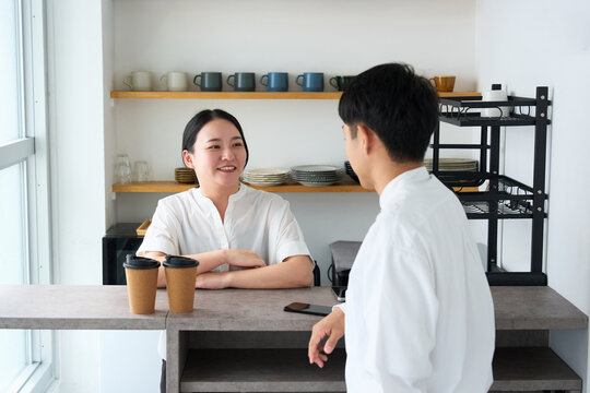 Young Japanese Woman Laughing and Talking with Cafe Staff at Counter