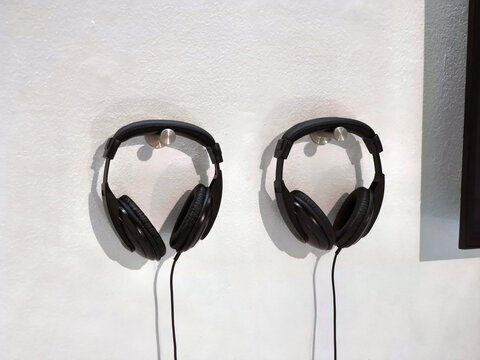 Two Black Headphones Hanging on White Wall
