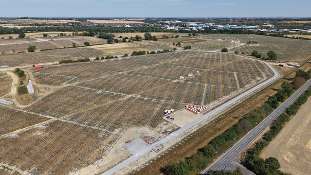 Aerial view of the Common Park Solar Farm under construction with rows of metal mounting structures, dirt tracks, and construction materials in Sheffield, England, United Kingdom.