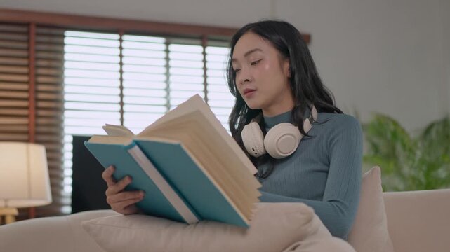 Young asian woman reading book on sofa