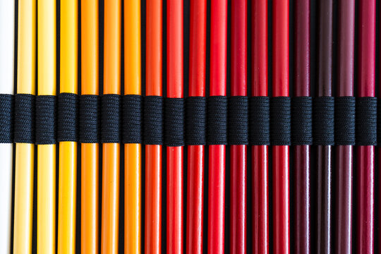 close-up of yellow orange and red colored pencils neatly lined up in pencil case, concept of creativity, drawing, education and art supplies