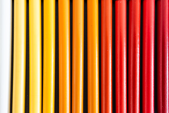 close-up of yellow orange and red colored pencils neatly lined up in pencil case, concept of creativity, drawing, education and art supplies