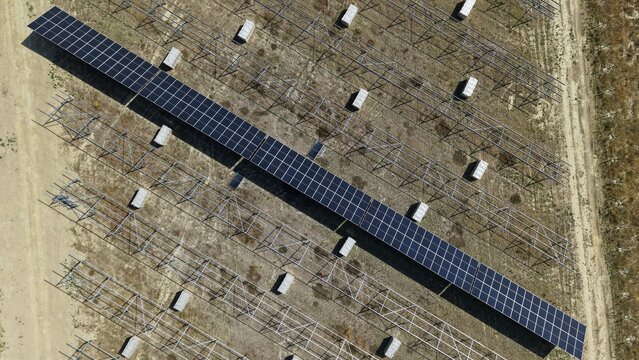 Aerial view of the Common Park Solar Farm under construction, showing rows of solar panels and metal mounting structures on a dry field in Sheffield, England, United Kingdom.