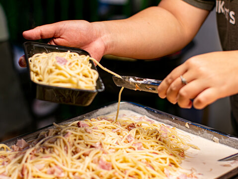 Vendor Pouring Creamy Sauce Over Spaghetti in Takeaway Box Street Food