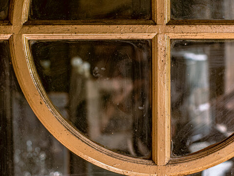 Close Up of Antique Gold Painted Window Frame with Dusty Glass and Blurred Reflection