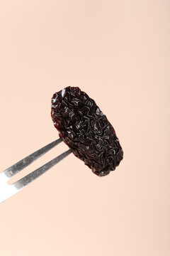 Xinjiang Black Jujube Dried Fruit with Chopsticks on Pink Background
