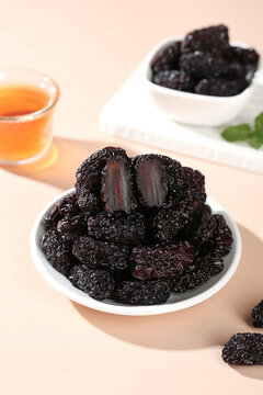Dried Black Jujube Fruits from Xinjiang in Bowl with Tea - Traditional Chinese Healthy Snack