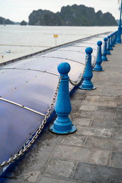 A tranquil coastal pathway with blue railings overlooking serene waters.