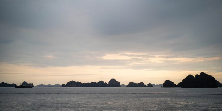 Serene landscape of rock formations silhouetted against a cloudy twilight sky.