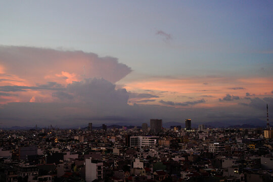 Vibrant sunset over a bustling city skyline silhouetted against colorful clouds.
