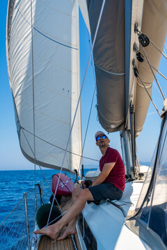 Man monitoring the mainsail while sailing a yacht offshore. Seamanship and navigation skills during a long distance voyage.