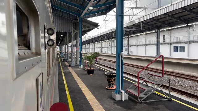 train in station. ide view of a passenger train stopped at an empty covered railway station platform with tracks and blue steel pillars